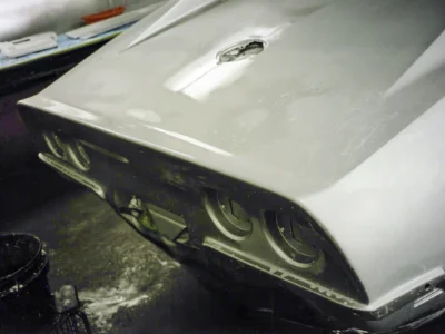Close-up of 1968 Corvette front nose and headlight area during primer stage