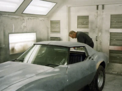 1968 Corvette in primer inside the paint booth with hood and body panels aligned.