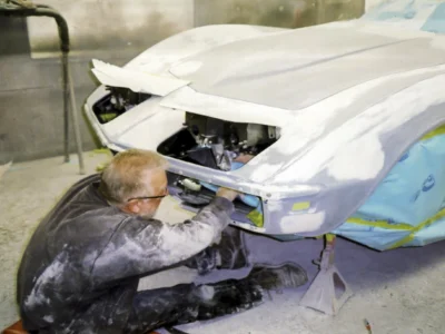 Technician working under the front end of a 1968 Corvette during restoration