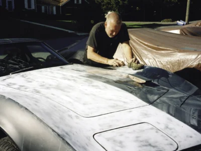 Technician sanding the front body panel of a 1968 Corvette during restoration at Corvette Connection in Bolton, CT