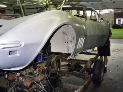 Side view of 1968 Corvette body shell mounted above the chassis during restoration.