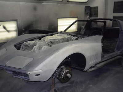 1969 Corvette body in white primer inside the paint booth with front fender exposed