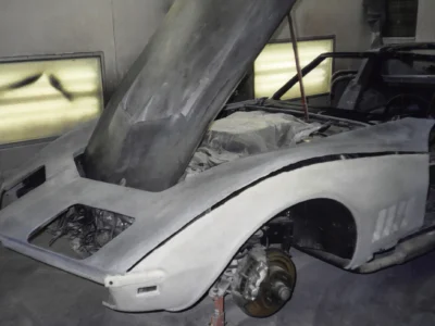 1969 Corvette hood raised inside the paint booth during primer preparation.