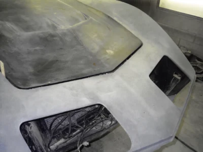 1969 Corvette front body section in primer with headlight opening exposed.