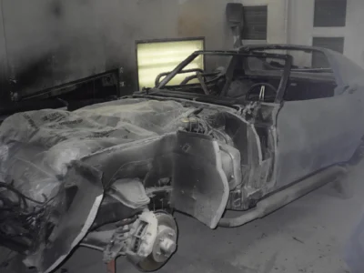 1969 Corvette body in primer inside the paint booth during restoration.