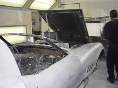 1969 Corvette front body section in primer with hood raised.