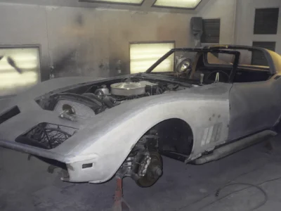 1969 Corvette body in white primer with front wheel removed during paint preparation.
