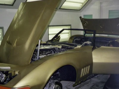 Gold 1969 Corvette with hood raised during mechanical assembly.