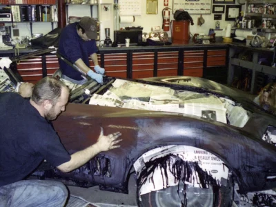 Technicians sanding and repairing the body side of a 1969 Corvette.