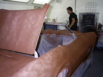 1969 Corvette in red primer with hood raised during bodywork.