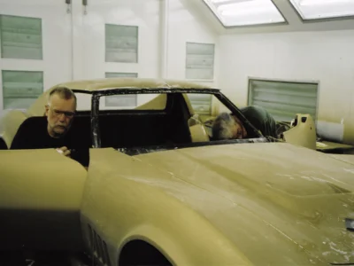 Technician working beside a gold 1969 Corvette during final assembly.