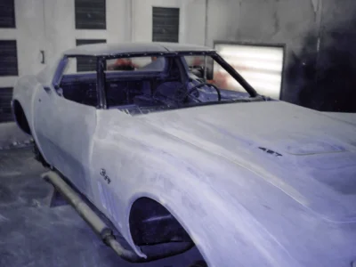 1969 Corvette body in white primer inside the paint booth during restoration.