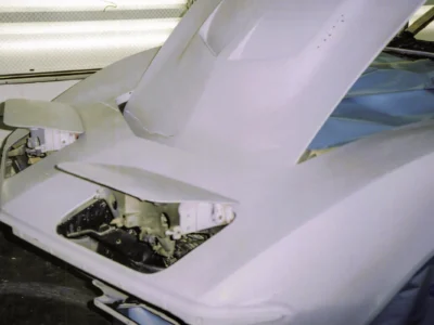 1969 Corvette rear body section in white primer with masked engine bay opening.