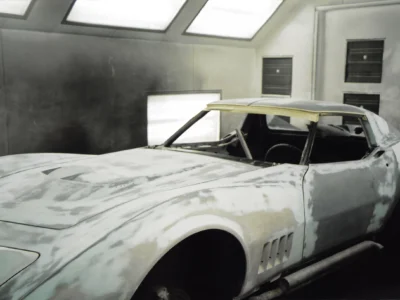 1969 Corvette body in primer with sanding marks inside the paint booth.