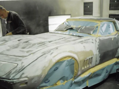 Technician sanding the front body section of a 1969 Corvette.
