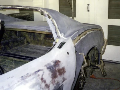 Rear quarter view of 1970 Corvette body in primer with repair areas visible.