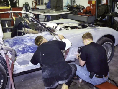 Technicians sanding the 1970 Corvette front body panels during restoration.
