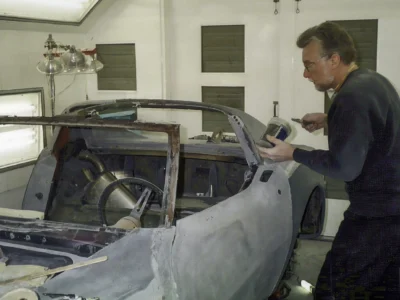 Technician inspecting the side of a 1970 Corvette body during restoration.