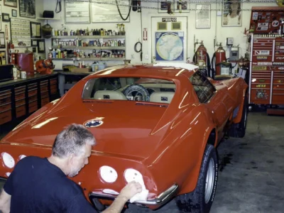 Technician working on the rear lights of a red 1970 Corvette during final assembly.