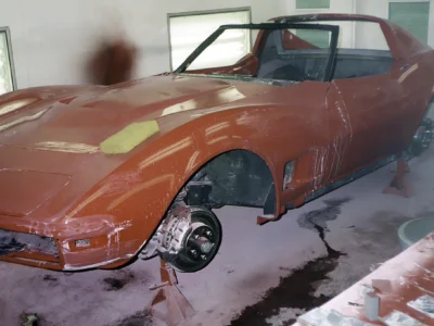 1970 Corvette front fender and body section in red primer during restoration.