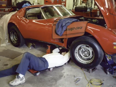 Technician working under a 1970 Corvette parked inside the shop.