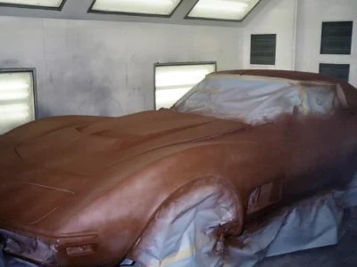 1970 Corvette in red primer inside the paint booth during restoration.