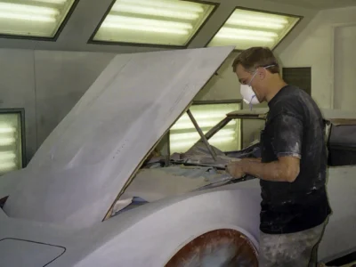 Technician sanding a 1970 Corvette body panel inside the paint booth.