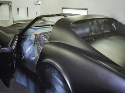Rear quarter view of 1970 Corvette body in dark primer during paint preparation.