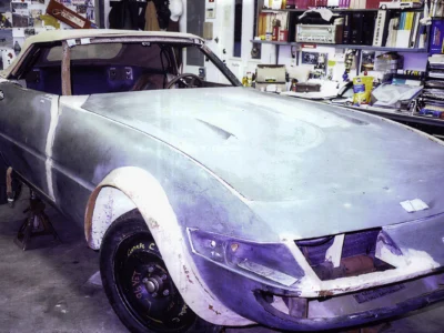 McBurnie Daytona Spyder in primer front three-quarter showing headlight area and whitewall tires