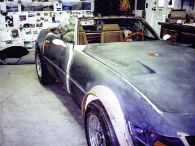 McBurnie Daytona Spyder in dark primer rear three-quarter showing body lines and whitewall tires