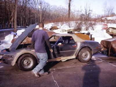 Technician working on McBurnie Daytona Spyder outdoors in winter at Corvette Connection