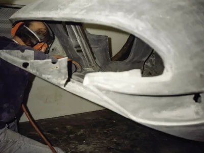 Technician sanding McBurnie Daytona Spyder body panel during fiberglass repair at Corvette Connection