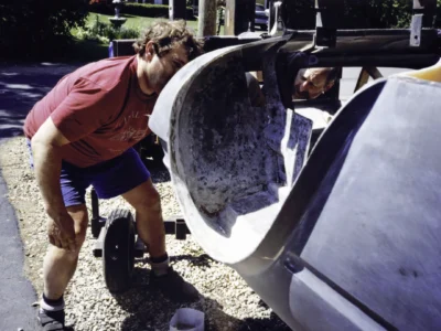 Technician fitting McBurnie Daytona Spyder fiberglass body panel outdoors at Corvette Connection
