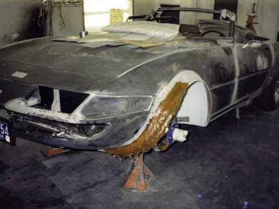 McBurnie Daytona Spyder body in primer showing fiberglass repair areas on jack stands