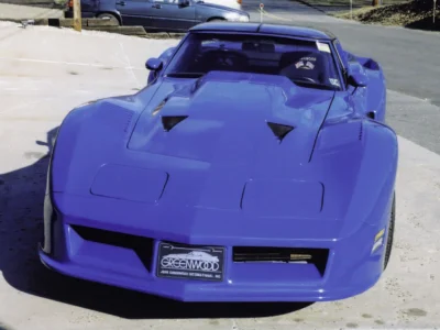 Remastered photo of a blue 1979 Chevrolet Corvette coupe front view, showing the hood vents, low front end, and restored late C3 Corvette styling.