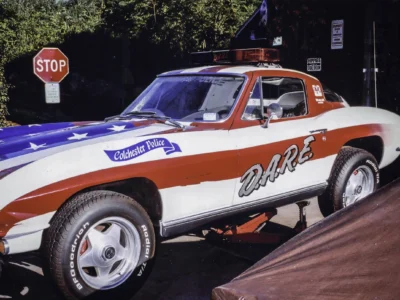 Remastered photo of a patriotic red, white, and blue 1970s Chevrolet Corvette pace car side view, showing custom graphics, race-style lettering, and restored exterior finish.