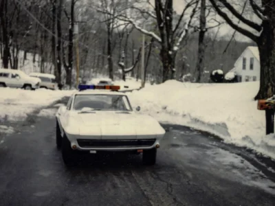 Remastered photo of a white 1967 Chevrolet Corvette coupe driving on a snowy road in Connecticut, showing the front view of the classic Sting Ray after restoration work by Corvette Connection.
