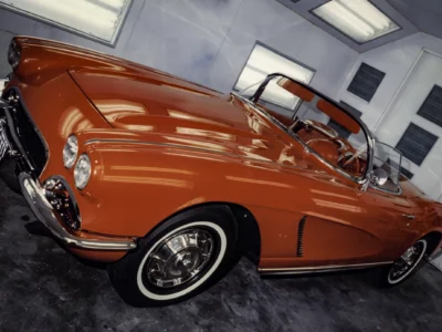 Remastered close-up photo of a red 1965 Chevrolet Corvette convertible wheel, fender, and side body detail, showing the restored paint finish and chrome trim work by Corvette Connection.