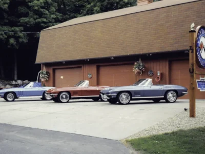 Remastered photo of red and blue classic Chevrolet Corvettes parked outside the Corvette Connection restoration shop in Bolton, Connecticut, showing multiple completed vehicles on display.