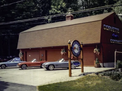Remastered photo of classic Chevrolet Corvettes parked outside the Corvette Connection restoration shop in Bolton, Connecticut, showing the original shop building, sign, and vehicle lineup.