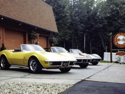 Remastered photo of yellow, white, and silver classic Chevrolet Corvettes lined up outside Corvette Connection in Bolton, Connecticut, showing multiple restored vehicles near the shop entrance.