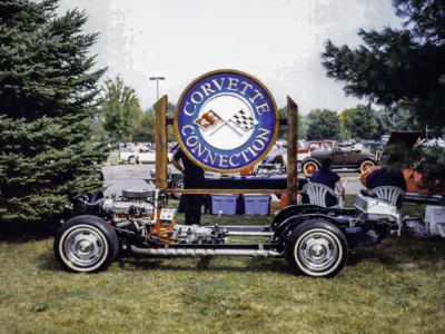 Remastered photo of a 1957 Chevrolet Corvette rolling chassis restoration displayed in front of the Corvette Connection sign at a car show in Bolton, Connecticut.