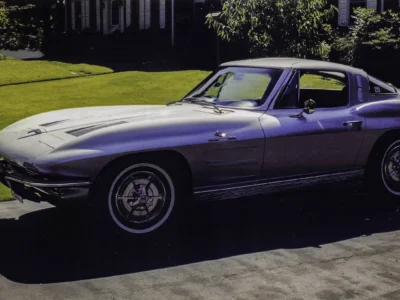 Remastered photo of a silver 1963 Chevrolet Corvette split-window coupe side profile, showing the fastback roofline, polished wheels, and restored mid-year Corvette body.